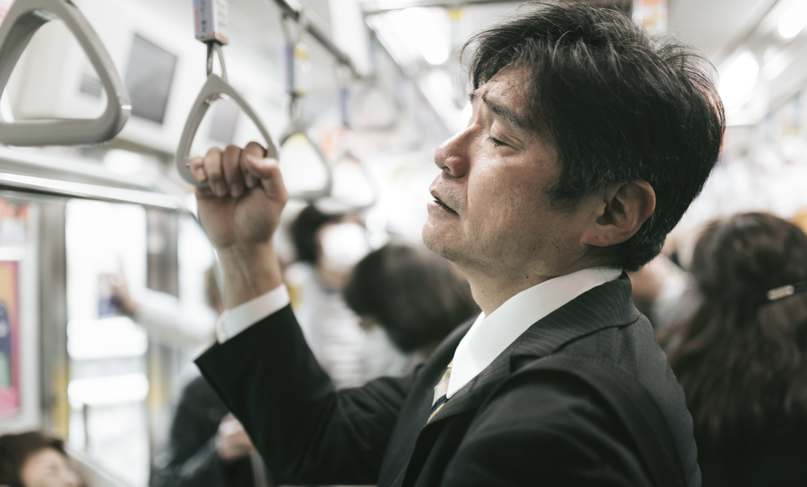 電車で立って寝る男性の画像