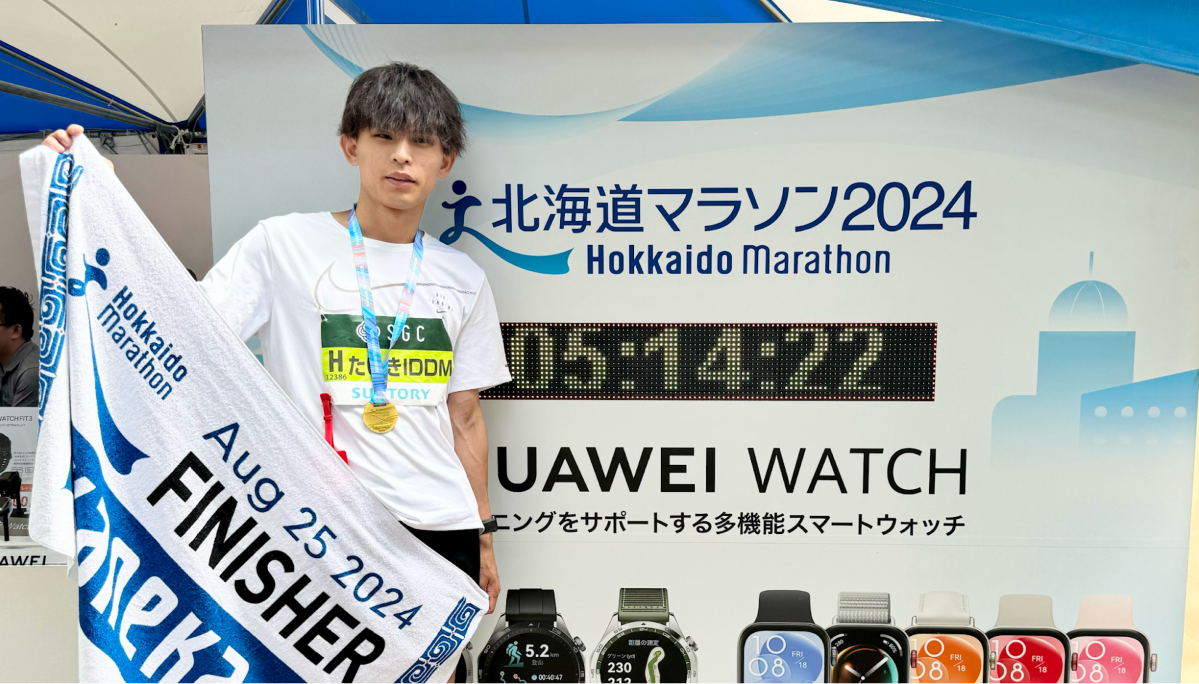 マラソン記録の横に並ぶ本間さん