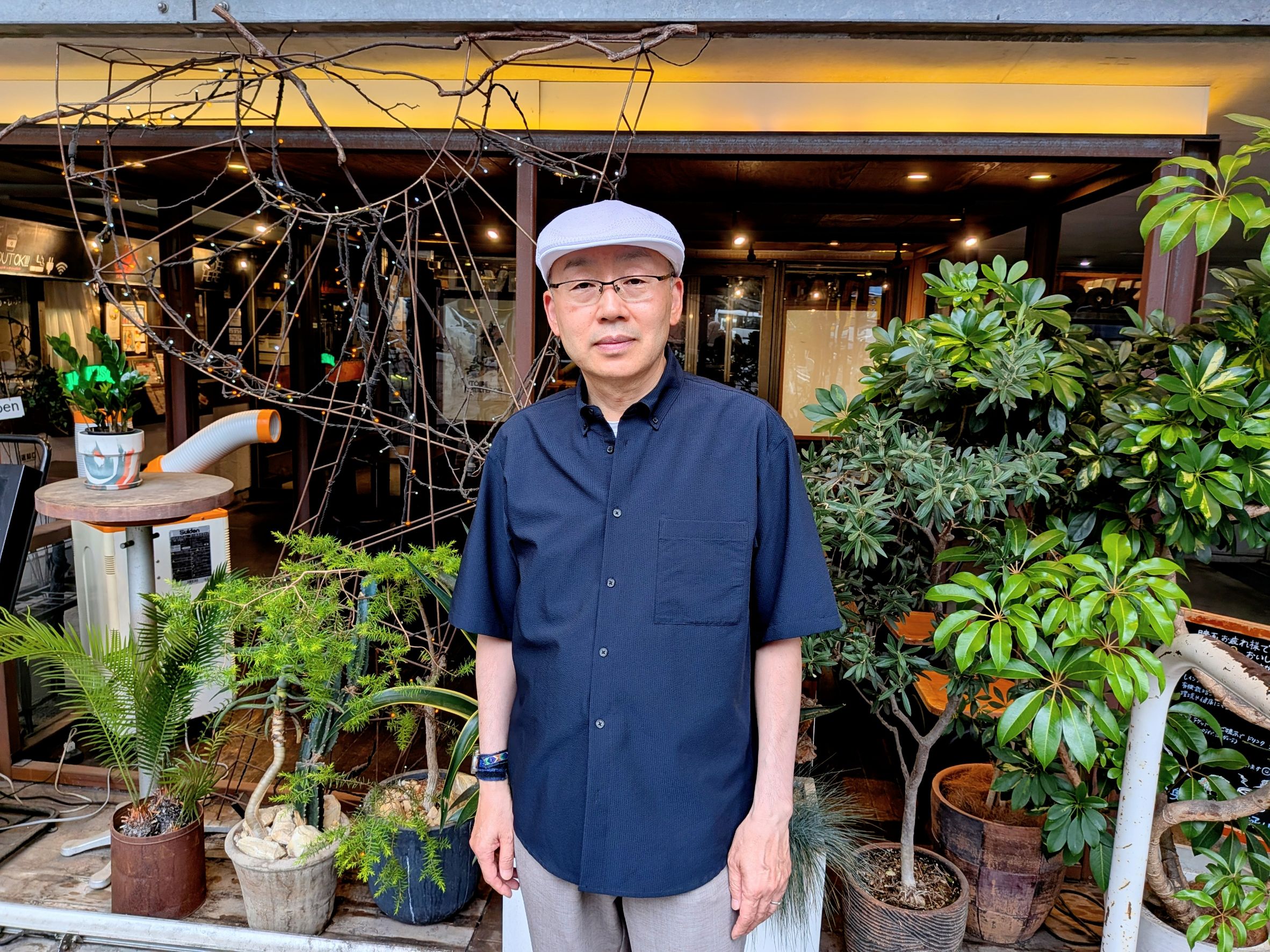 カフェを背景に立つ、月乃光司さん