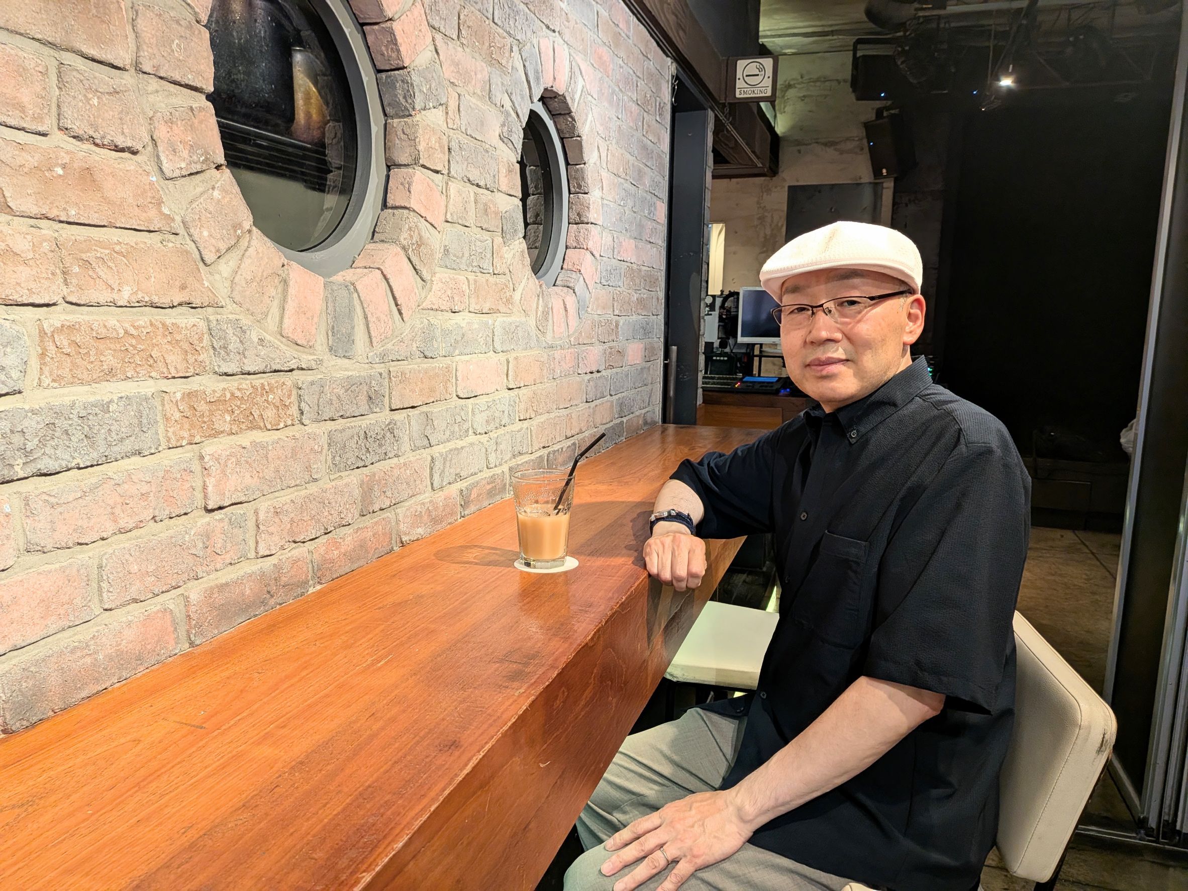 カフェのテーブルに腕をつき、こちらを見る月乃さん