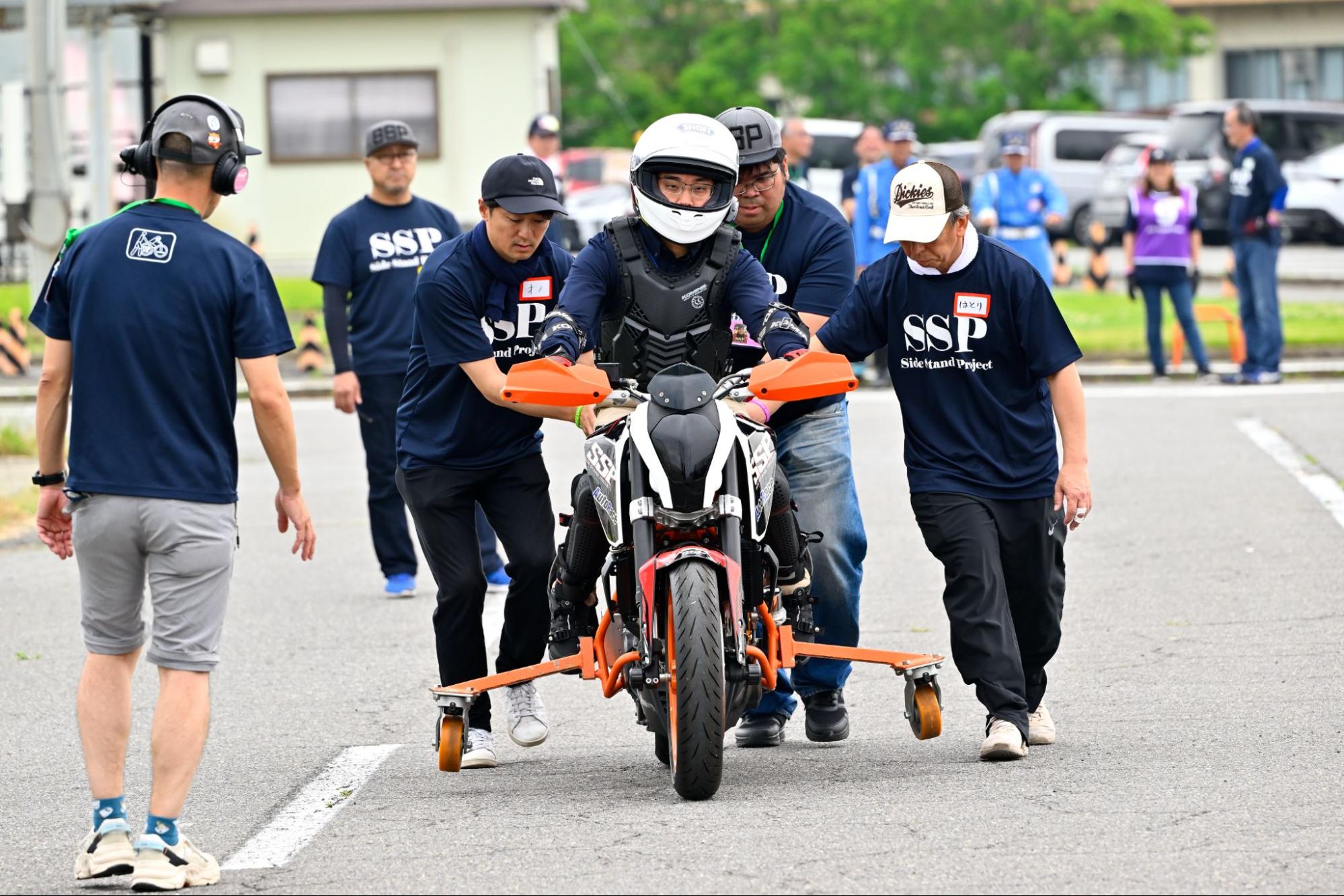 練習としてバイクに補助輪を付けて走ろうとする様子